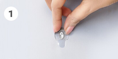 how to remove clear Command™ hooks step 1- hold hook gently in place 
