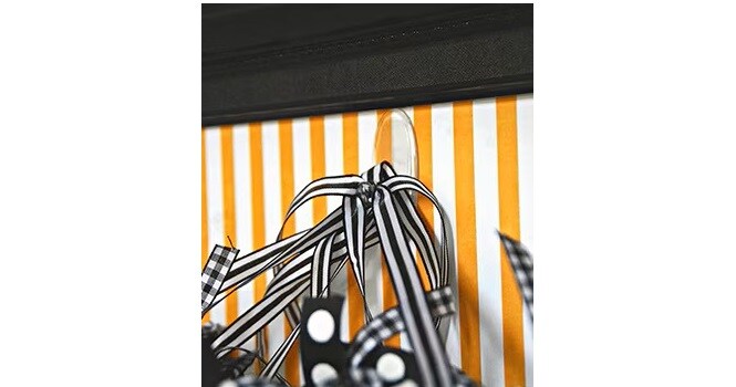 Adhere a Command™ Clear Medium Hook inside a black picture frame with orange patterned scrapbook paper inside

