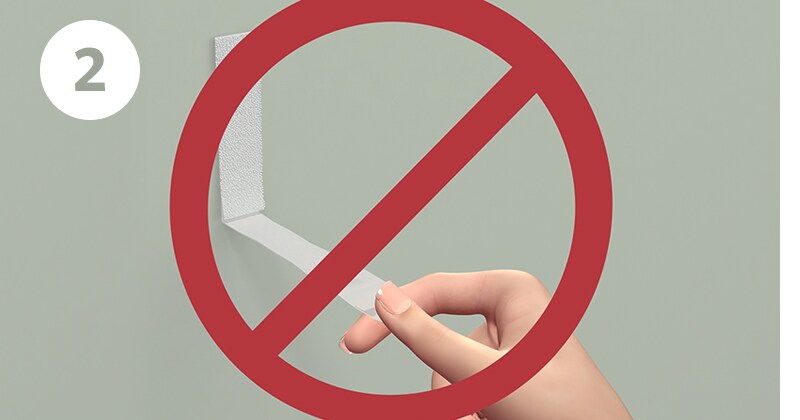 Step 2 of removing Command™ strips - pull straight down on the strip; not pulling away from wall
