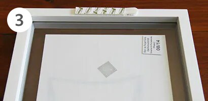 Applying command picture hanging strip to the back of the frame
