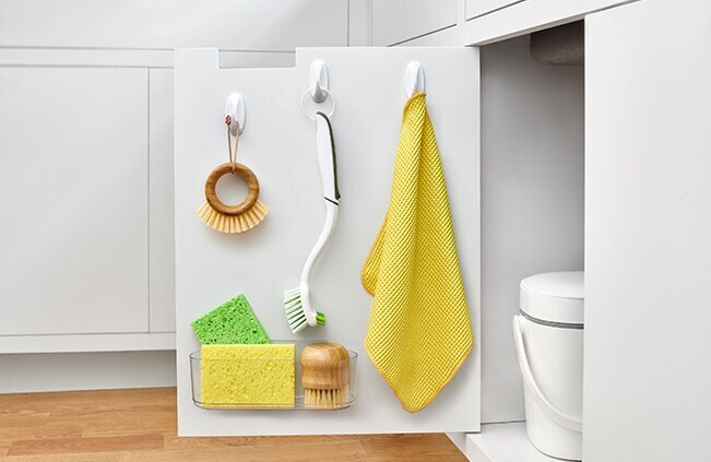 Image of cleaning tools hanging on a cabinet door using Command Hook