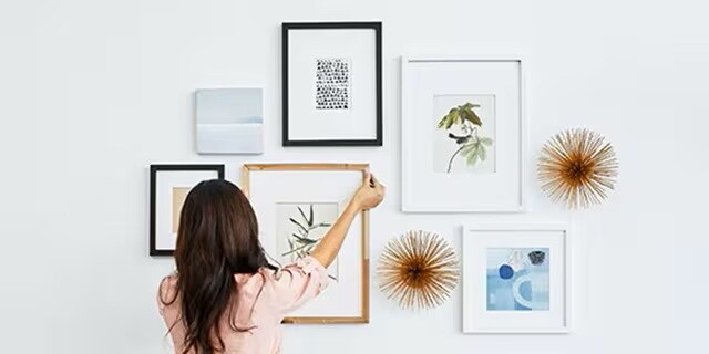 woman hanging picture frames using command